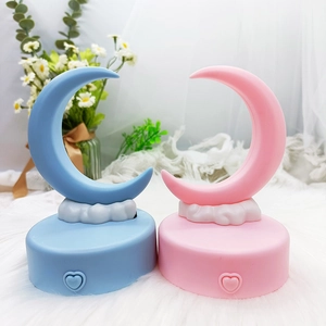Detail of moon-shaped night lights in pink and blue on white plush background