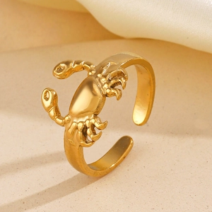 Bague ouverte scorpion dorée sur sable fin avec détails de soie luxueuse