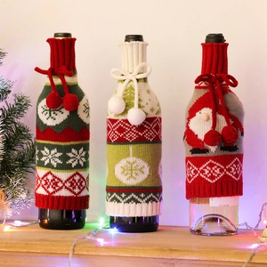 Three festive knitted Christmas wine bottle covers with snowflakes and pom-pom designs