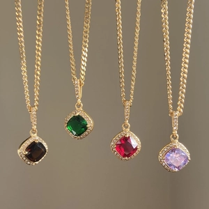 Close-up of gold Cuban chains with square gemstone heart pendants in multi-color