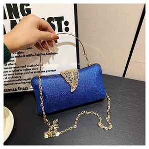 Close-up of blue glitter evening bag featuring a gold leaf clasp and metal chain handle
