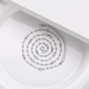 Detailed macro view of S925 sterling silver chain with bead accents on white background