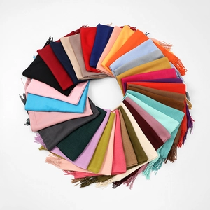 Detailed overhead view of assorted solid cashmere-feel scarves with fringe in vibrant colors