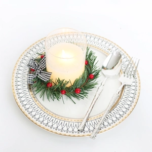 Christmas candle ring with holly berries, plaid bow and pine needles on a gold-rimmed plate