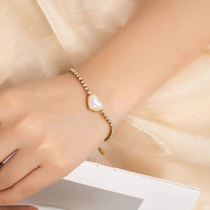 Close-up of golden titanium steel bracelet with heart pendant and micro-set rhinestones