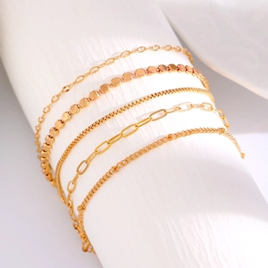 Detail eines fünfteiligen Goldketten-Armband-Sets auf einer weißen Zylinderstütze