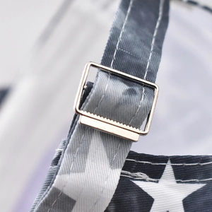 Detail of adjustable metal buckle and star pattern fabric strap on a baseball cap