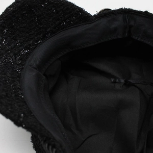 Detail of black tweed newsboy hat showing woven texture and inner sweatband lining