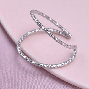 Detail of silver double-layered open ring with hammered texture on pink background