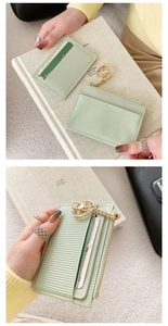 Close-up of light green PU leather coin purse with gold chain held by a model