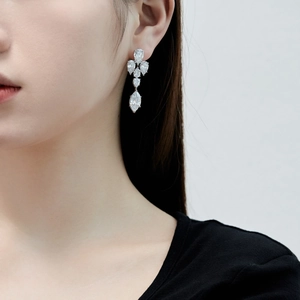 Détail de longues boucles d'oreilles argentées avec zircon poire portées par le mannequin