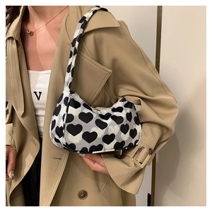 Détail du sac baguette en toile à motif cœur porté avec un trench-coat kaki élégant