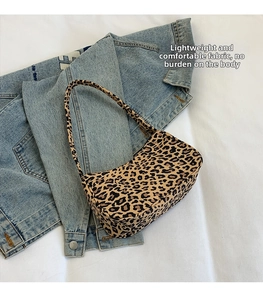 Détail à plat du sac croissant imprimé léopard sur veste en jean et tissu texturé