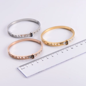 Close-up of hollow Roman numeral bangles with sparkling pave diamond inlay in three colors