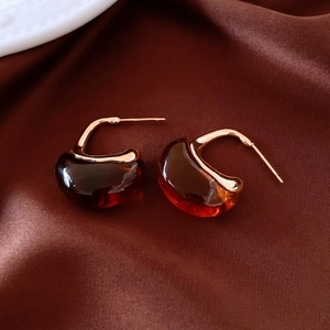 Macro view of 18k gold plated hoop earrings with amber resin and silk texture background
