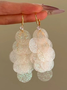 Macro detail of cascading iridescent sequins and zircon stones on C-shaped fringe earrings