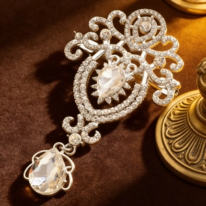 Macro view of vintage silver crystal brooch with intricate filigree and teardrop pendant