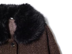 Détail d'un manteau marron texturé avec un col épais en fausse fourrure noire et bouton