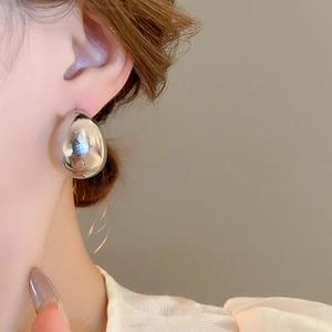 Gros plan d'une boucle d'oreille goutte d'argent sur modèle avec éclat métallique