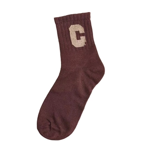 Detail view of a brown cotton mid-calf sock featuring a knitted beige letter C pattern