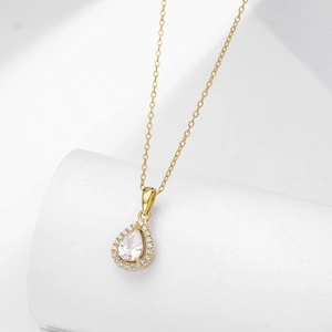 Macro view of pear-shaped halo necklace with gold chain and teardrop zircon pendant