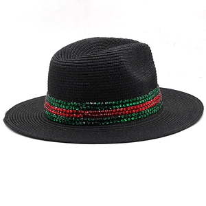 Detail of black straw fedora hat featuring green and red rhinestone stripe decoration