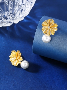 Macro shot of elegant gold flower earrings with white pearls and sparkling zircons