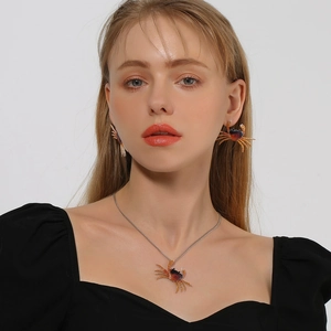 Detalle de conjunto de collar y pendientes con forma de cangrejo usados por una modelo