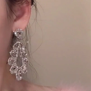 Elegant silver-toned hollow teardrop earrings with sparkling rhinestones worn by a model