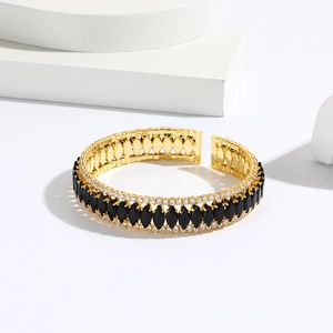 Detail of luxury gold bangle featuring marquise-cut black stones and micro-pave crystals
