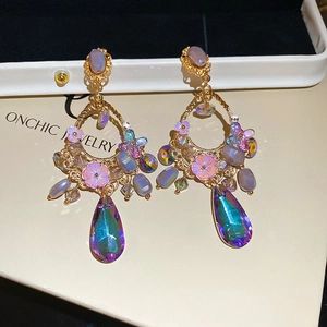 Detail of floral earring with purple crystals and large iridescent teardrop pendant