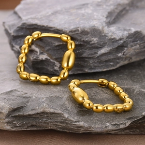 Detail of 18k gold plated square zircon earrings on natural grey stone background