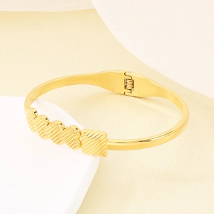 Detailed view of gold hollow heart and square links on a textured stainless steel bracelet