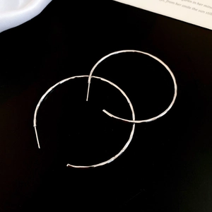 Détails des créoles argentées avec une finition en métal martelé artisanal