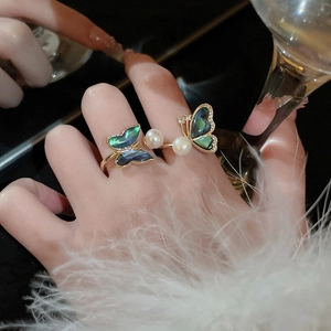 Detail of gold butterfly ring with pearl and abalone shell worn on finger