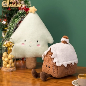 Detail view of plush Christmas tree and gingerbread house doll pillows on a wooden surface