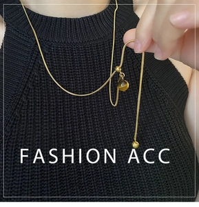 Détail du pendentif en œil de tigre sur une chaîne serpent dorée portée sur un pull noir
