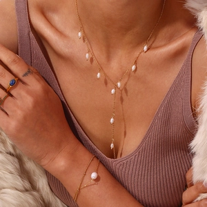 Détail d'un ensemble collier en Y avec perles, bracelet et bagues dorées sur mannequin