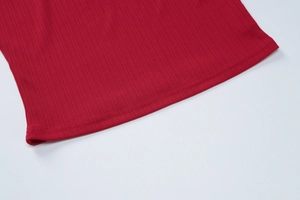 Gros plan sur la texture du tricot côtelé rouge et les détails de couture sur l'ourlet