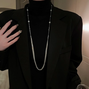 Multi-layer silver long necklace with pearl accents on a black turtleneck sweater