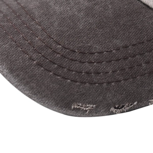 Detailed close-up of distressed brim on washed black denim baseball cap with four-row stitching