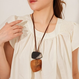 Close-up of a long irregular square resin pendant on a dark brown rope necklace