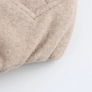 Detailed macro view of light brown wool bomber jacket fabric texture and quality stitching