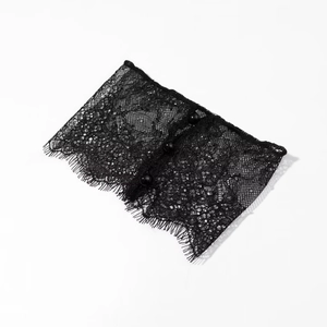 Détail de poignets en dentelle florale noire avec des boutons élégants et bords en cils
