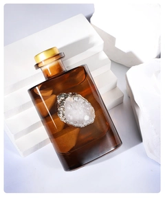 Amber glass diffuser bottle with white agate slice on a white geometric platform