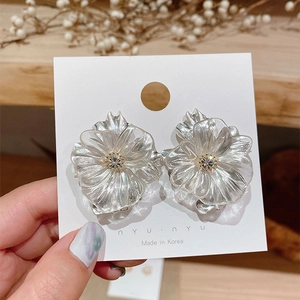 Minimalist clear crystal flower stud earrings with silver pins on a display card