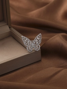 Close-up of a silver butterfly ring with sparkling cubic zirconia on brown silk background