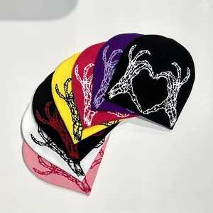 Flat lay of knit beanies in various colors featuring a skeletal heart jacquard pattern