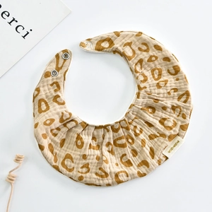 Detail of baby leopard print cotton bib with ruffled edge and snap closure on white
