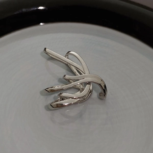 Detailed view of silver butterfly tassel ear clip on a clean monochrome ceramic plate